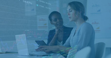 Female professionals in business attire collaborating in office, with laptop, tablet, data overlay