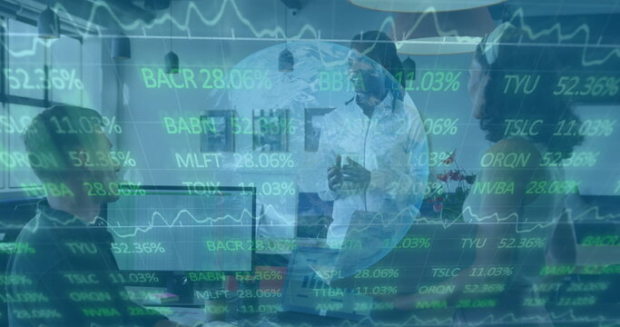 Presenting white male executive gesturing at meeting table, with monitors and stock-ticker overlay