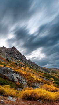 Windswept fall sky with fast-moving gray clouds above a mountain ridge in autumn