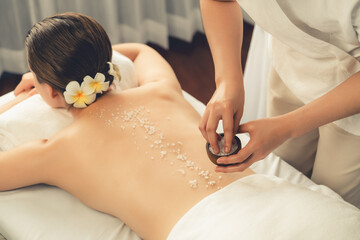 Woman customer having exfoliation treatment in luxury spa salon with warmth candle light ambient....
