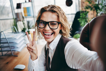 Joyful professional businesswoman winking and posing confidently at her office desk, creating a...