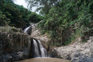 Cascading waters amidst lush greenery in remote mountain landscape with natural rock formations and vibrant vegetation