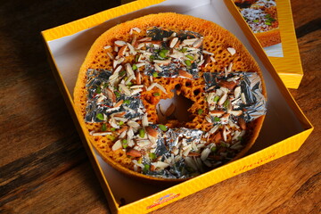 Indian Traditional Sweet Ghevar with Dry Fruits and Silver Leaf in Yellow Box on Wooden Background – Festive Dessert Close-up