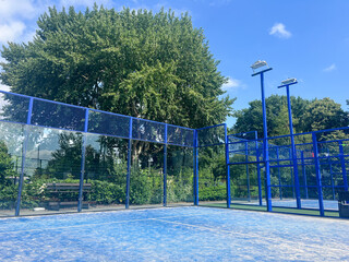 Modern outdoor padel courts with vibrant blue surfaces under sunny skies, offering perfect conditions for this exciting racket sport that combines tennis and squash elements. 