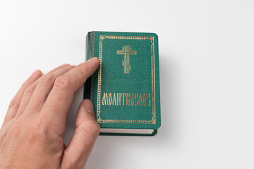 A prayer book on a white background. A believer's hand reaches for a prayer book