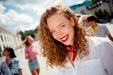 Cheerful young woman enjoying outdoor day with friends in urban setting, sharing laughter during a...
