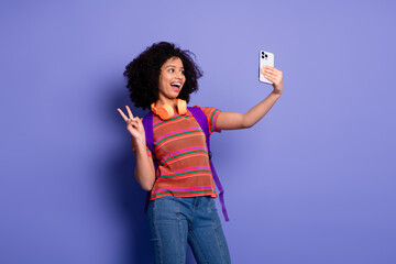 Energetic young woman posing with a smartphone in a lively and cheerful mood against a vibrant...