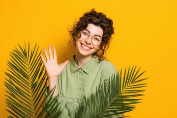 Cheerful woman with a charming smile waves against a bright backdrop