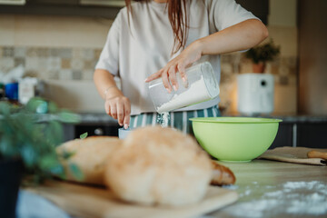Young caucasian woman making bread dough with rolling pin and flour	
