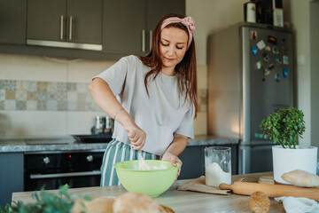Young caucasian woman making bread dough with rolling pin and flour	
