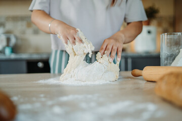 Young caucasian woman making bread dough with rolling pin and flour	
