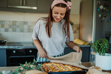 Young caucasian woman making bread dough with rolling pin and flour	
