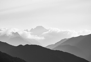 Misty monochrome mountain range, dramatic peaks shrouded in fog,  tranquil,  mountain