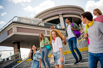 Happy youthful friends enjoying time together outdoors in the city on a sunny day with smiles and...