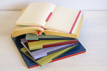 Stack of colorful books and open notebook on white rustic table. Back to school. Copy space