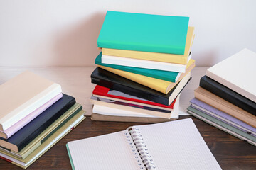 Stacks of different colorful books and open spiral bound notebook on rustic table. Back to school. Copy space