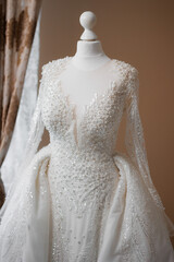 Elegant white wedding dress adorned with intricate beading and flowing sleeves on display