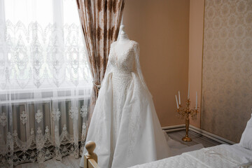 Elegant wedding dress displayed in a bright room with soft lighting and decorative curtains