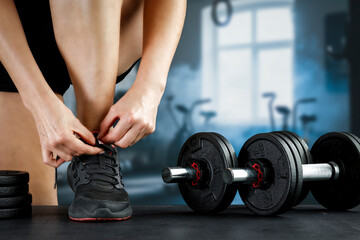 Close up of fit woman while intense strength workout in cinematic gym with sunlight and smoke –...