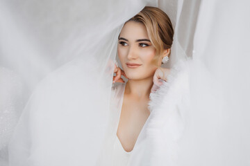 Beautiful woman posed elegantly behind delicate white fabric in a bright setting