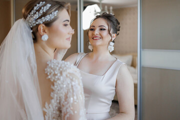 Bridesmaid helping bride prepare for wedding ceremony in elegant setting