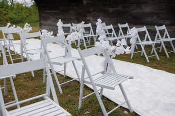 Charming outdoor wedding setup with white chairs and flower decorations in a serene setting