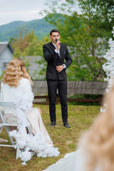 Wedding ceremony with groom speaking to bride and guests in outdoor setting