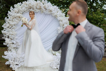 Couple in wedding attire poses in floral circle during outdoor ceremony