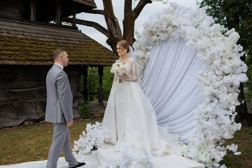 Wedding ceremony with floral backdrop in a rustic outdoor setting during spring afternoon