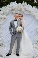 Couple celebrates wedding ceremony amid floral decorations and elegant attire in outdoor setting