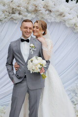 Couple celebrates their wedding in a floral backdrop at an elegant outdoor venue