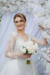 Elegant bride in floral setting holding bouquet during wedding ceremony