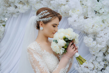 Elegant bride with bouquet surrounded by beautiful flowers during wedding ceremony