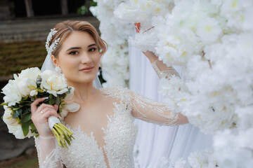 Bridal portrait featuring a smiling woman holding a bouquet in a floral setting