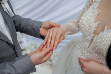 Couple exchanging wedding rings during their ceremony in an elegant indoor venue