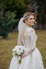 Elegant bride poses outdoors with bouquet in garden setting during daytime