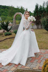 Elegant bride poses outdoors in stunning gown with bouquet during wedding preparations