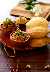 Luchi, Mix Vegetable and Dal Breakfast. A delicious spread of Indian food, featuring fluffy puri bread and two bowls of flavorful curries, garnished with fresh herbs.