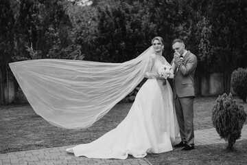 Couple celebrates wedding with elegant attire and flowing veil in garden setting
