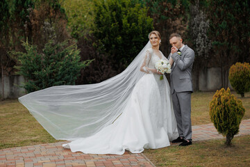 Couple celebrating their wedding day in a beautiful garden setting with flowing bridal veil