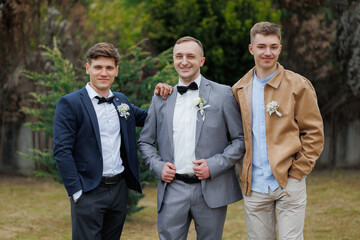 Men celebrate wedding day in outdoor venue surrounded by greenery with cheerful expressions