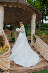 Bride in elegant gown poses in garden gazebo filled with flowers on a serene day