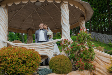 Couple posing in a gazebo surrounded by colorful greenery on their wedding day