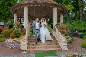 Couple celebrates wedding in beautiful garden gazebo with scenic greenery