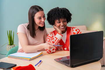Caucasian and African American students work together using a laptop and notebook. Focused and cheerful, they collaborate in a cozy indoor space, representing learning, diversity, and teamwork. 