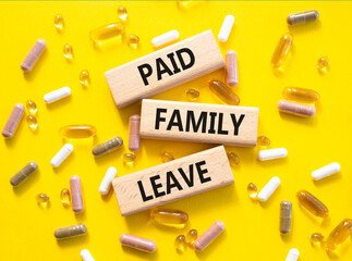 Paid Family Leave symbol. Concept words Paid Family Leave on wooden blocks. Beautiful yellow...