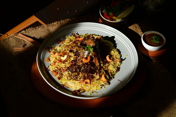 Mutton Mandi Rice. A delicious plate of biryani, a flavorful rice dish, served with a small bowl of curry and a side salad.