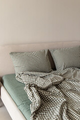 Green bed linen made of boiled cotton. Vertical. Plaid pillowcases and duvet cover