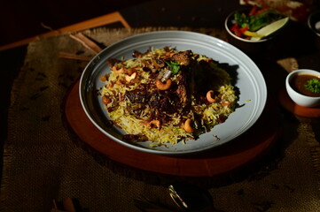 Mutton Mandi Rice. A flavorful and aromatic Indian biryani dish, served in a traditional bowl with garnishes and spices, presented in a warm, inviting light.