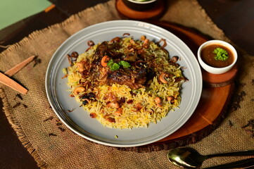 Mutton Mandi Rice. A delicious and aromatic plate of biryani, a flavorful rice dish, served with a side of chutney and salad, presented on a rustic wooden surface.